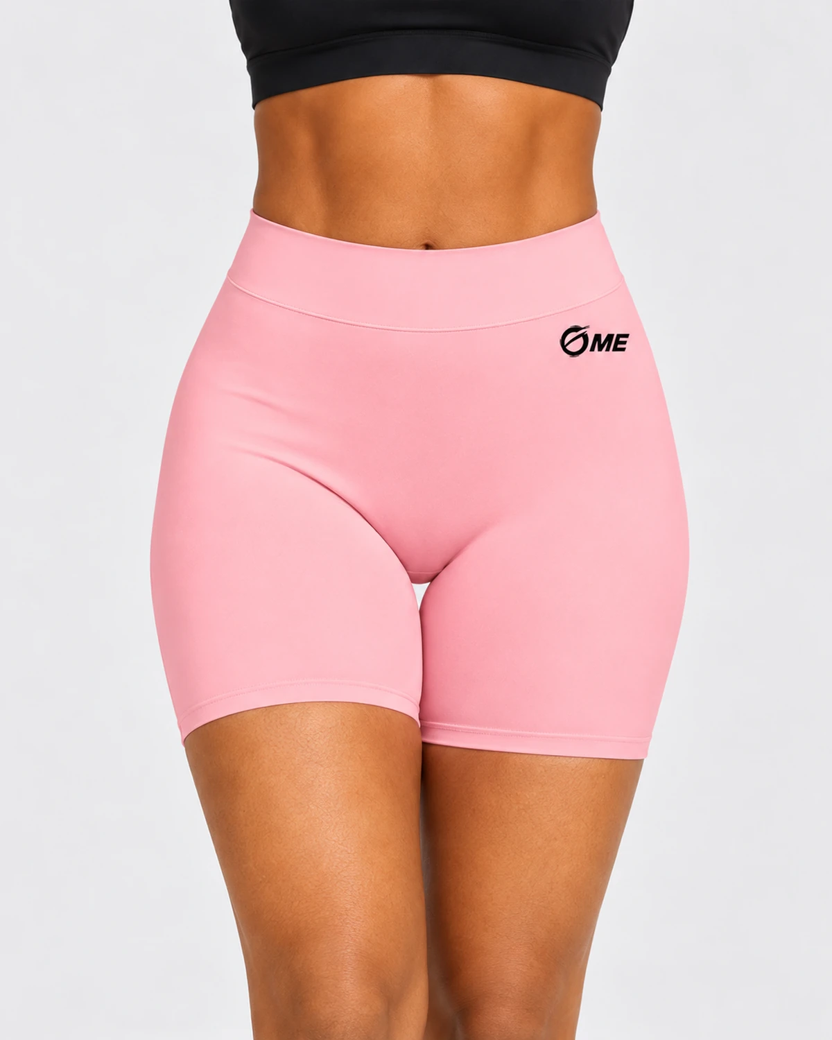 Detalle del logo OME negro y la cintura alta del pantalón corto ABDERA rosa sobre modelo.