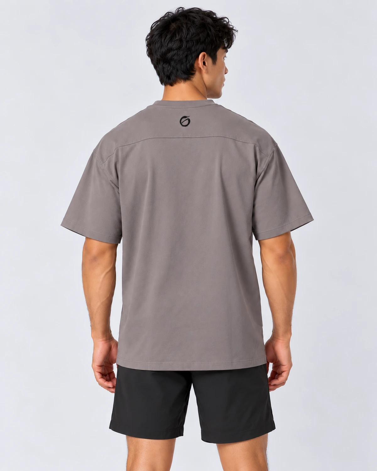 Camiseta MALAKA gris, vista trasera con modelo y símbolo negro bajo el cuello.