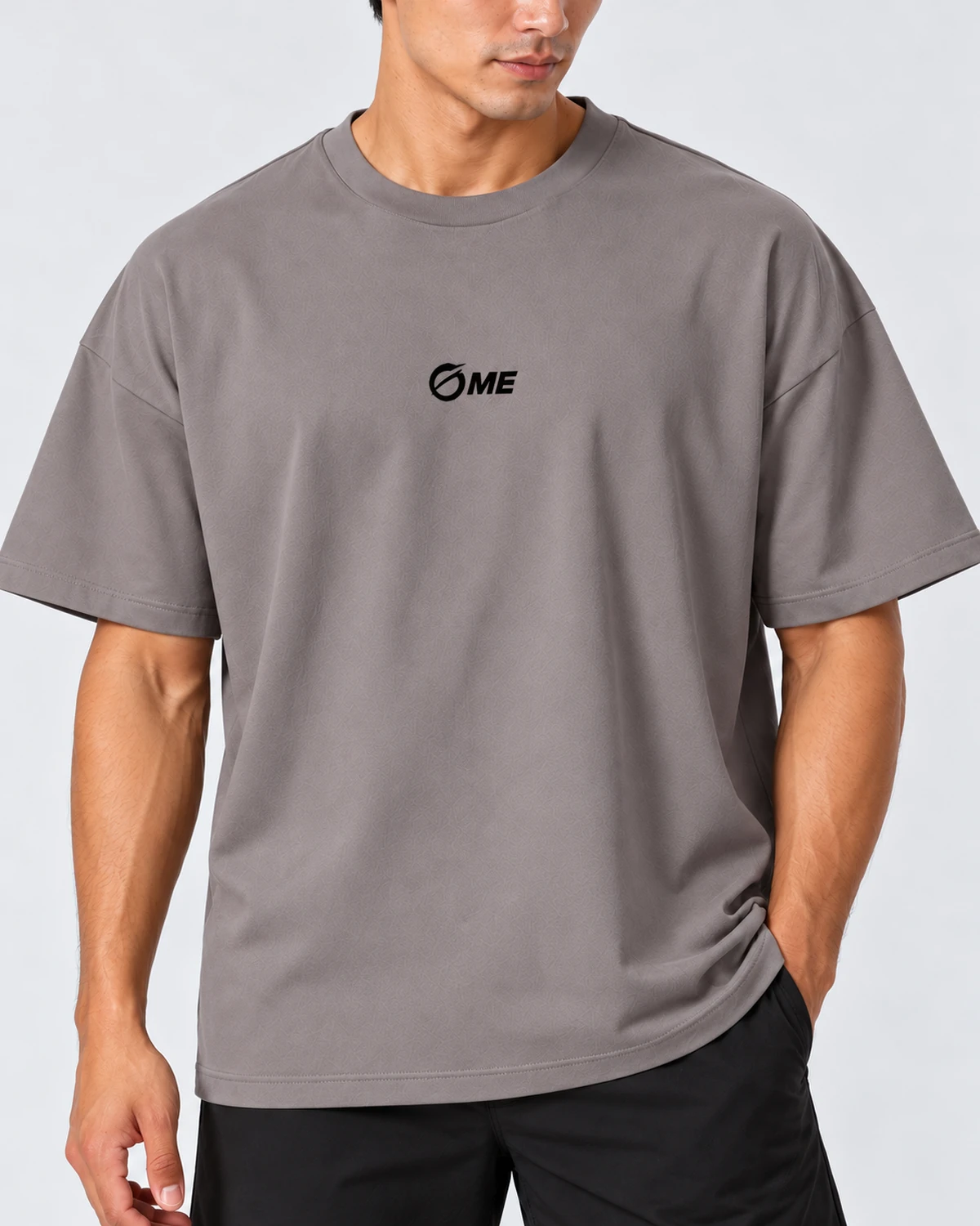 Detalle del logo OME negro y del cuello redondo de la camiseta MALAKA gris puesta en modelo.